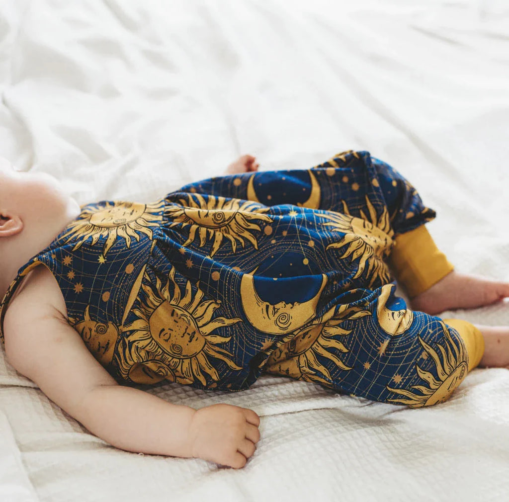90s child baby girl romper by Lottie & Lysh featuring gold sun and moon print with mustard cuffs at the ankles.