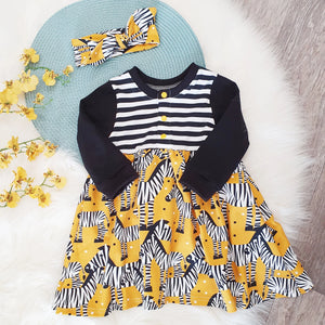 Lottie & lysh Mustard zebra dress. The dress features front opening poppers, black and white striped top with long black sleeves and gathered mustard zebra print skirt. The dress is photographed on a white fluffy background with yellow flowers to the left, and matching mustard zebra print knotted headband.