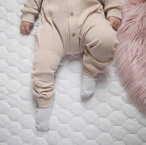 baby wearing Lottie & lysh beige baby romper with white socks