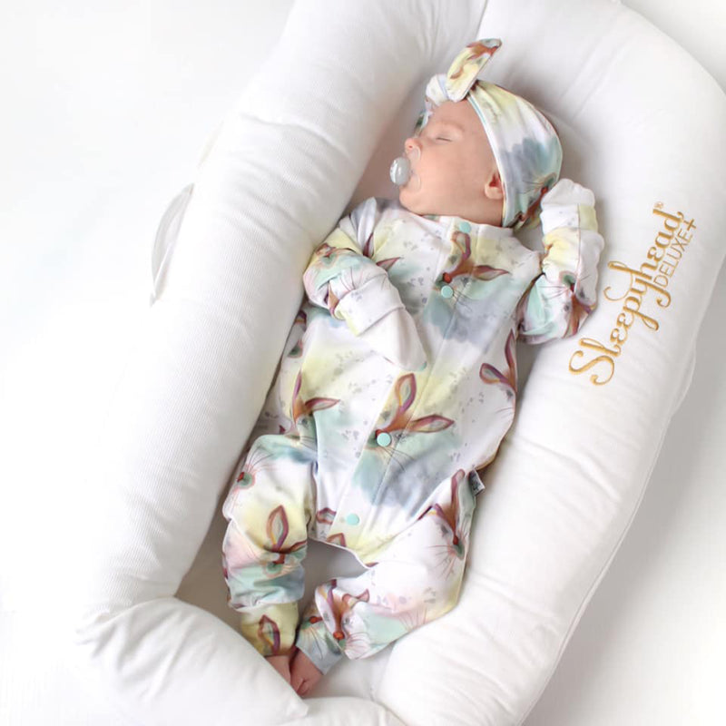 newborn baby girl wearing a Lottie & lysh pastel rabbit print baby romper with matching bow headband.