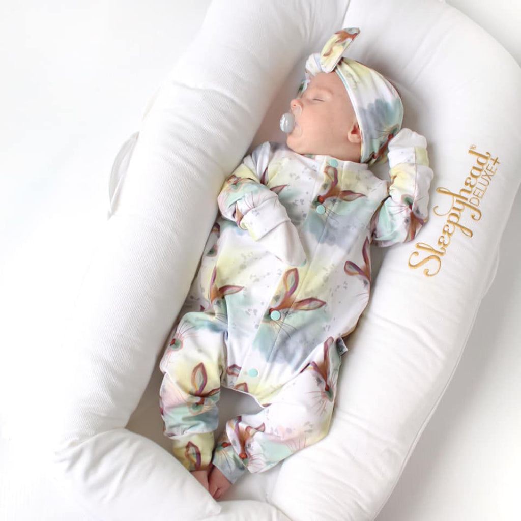 newborn baby girl wearing a Lottie & Lysh rabbit print babygrow with matching bow headband. Ethically made unisex newborn clothing available with worldwide shipping