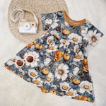 Handmade baby and toddler dress by Lottie & Lysh. Featuring white and orange flowers against a blue background, with bee detail. 