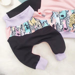 Close up flat lay image of Yo Mama Lottie & Lysh jogging bottoms for children and babies. The tracksuit is black and pink with a retro printed front panel