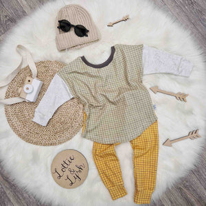 kids outfit flat lay image featuring L&L mustard grid leggings, sage green grid top, beige knitted beanie hat and black sunglasses