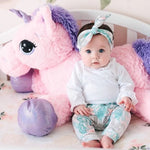 cute baby girl wearing lottie & lysh candy unicorn print leggings and matching headband set leaning against a large pink fluffy unicorn toy
