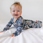 smiling baby boy wearing blue and white outfit printed with owls and snowy mountains